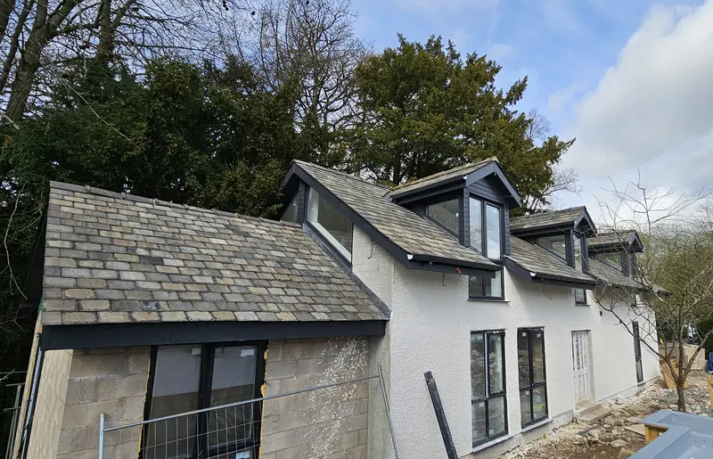 White rendered house with a traditional slate roof and three dormer windows