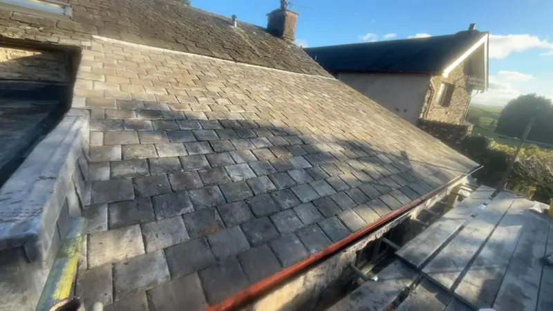 Traditional slate roof with lead flashing where it meets a stone wall